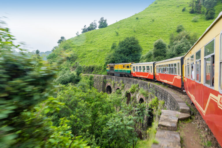 A heritage train crossing an arch bridge on the Kalka–Shimla Railway — one of the most iconic scenic train journeys in India.