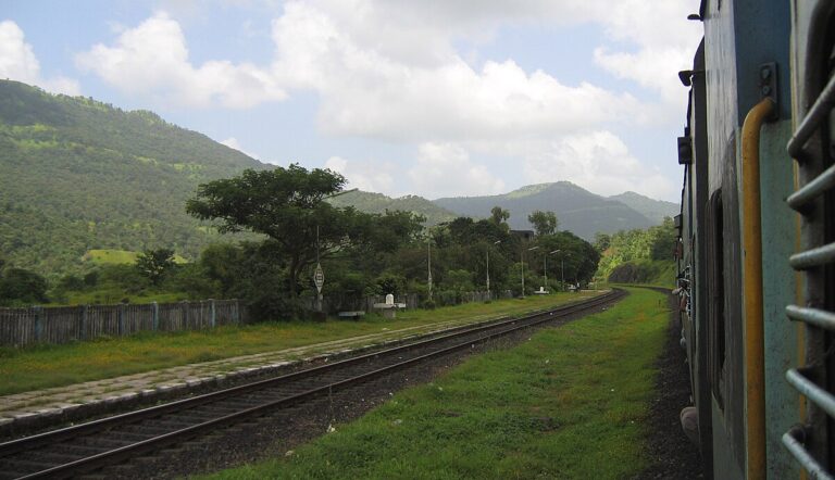 Photo of a train track winding through lush green hills of the Western Ghats along the Konkan Railway route.